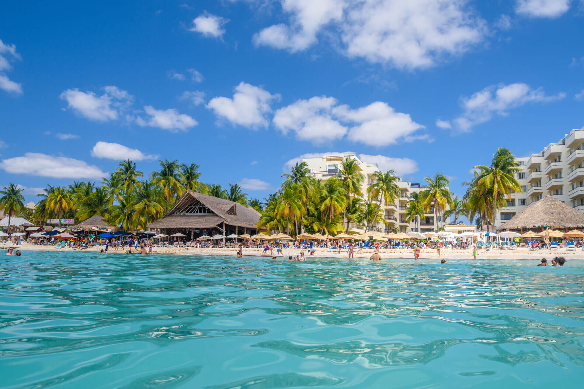 people-swimming-near-white-sand-beach-with-umbrellas-bungalow-bar-cocos-palms-turquoise-caribbean-sea-isla-mujeres-island-caribbean-sea-cancun-yucatan-mexico (1) (1)